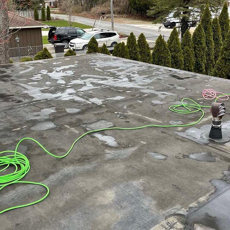 A green hose is laying on the roof of a building.