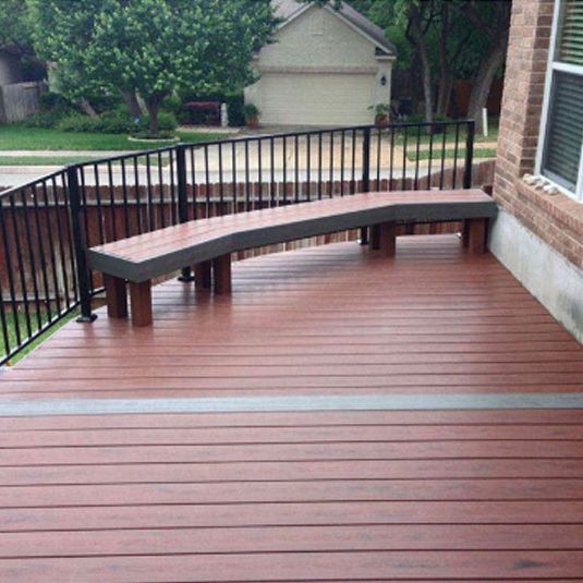 A wooden deck with a curved bench and a railing.
