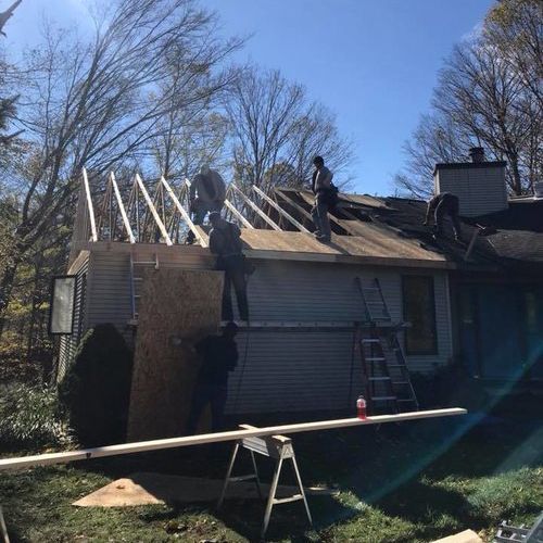 A group of men are working on the roof of a house.