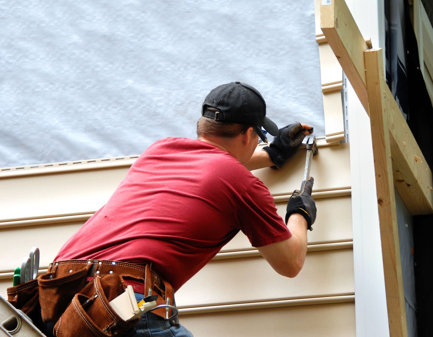 A man in a red shirt is working on a house