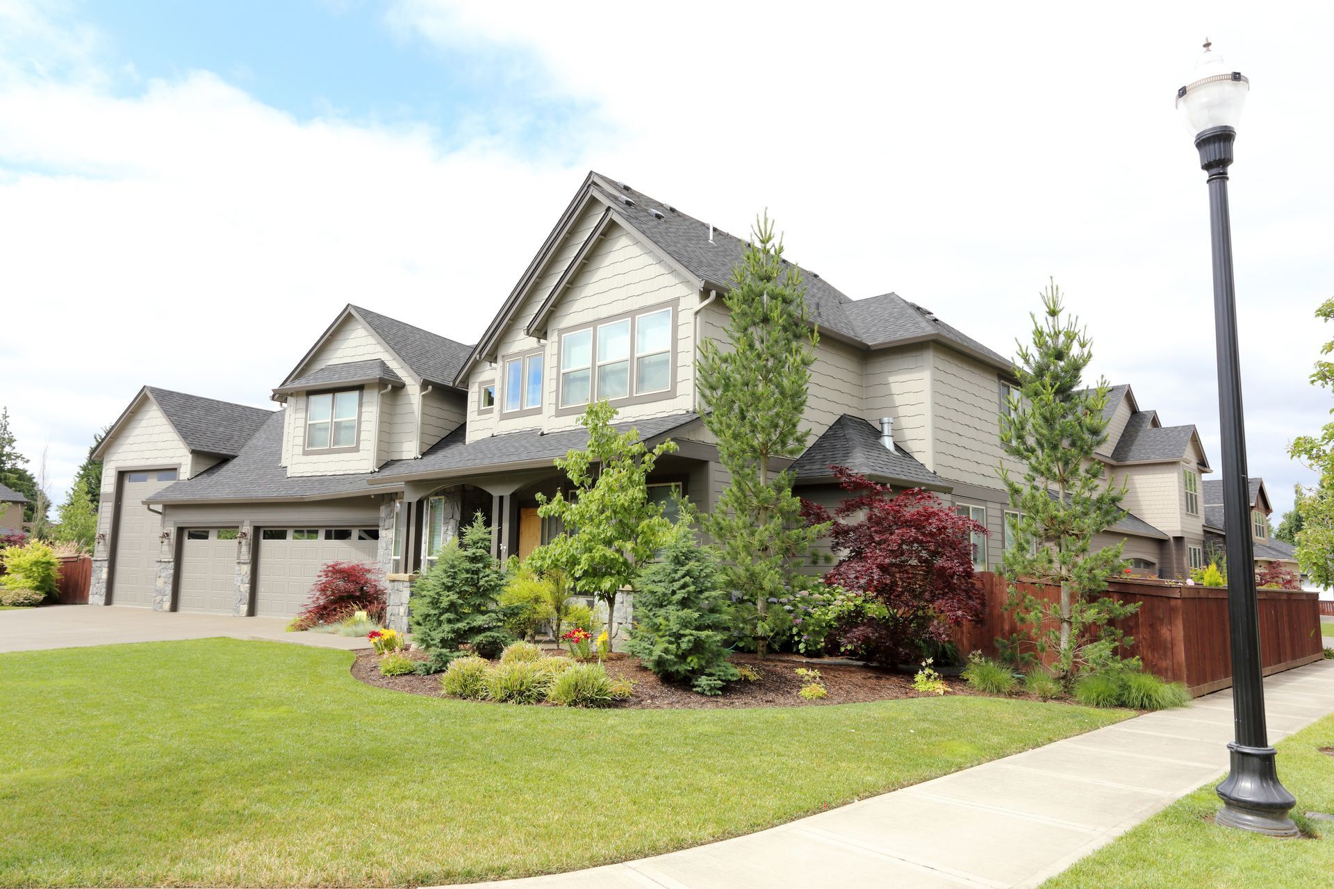 A large house with a lush green lawn and a street light in front of it.