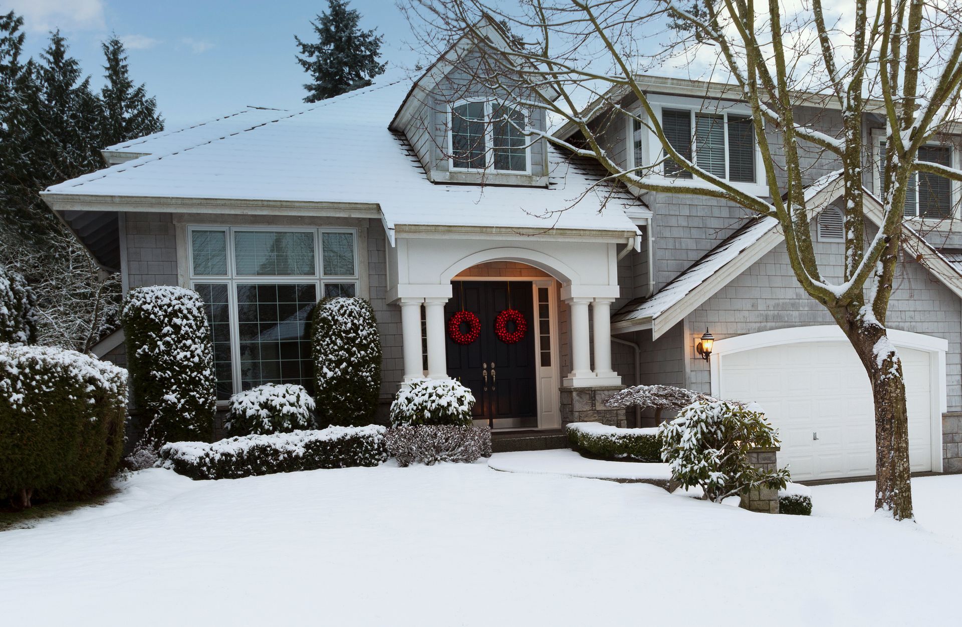A house with snow on the ground and a wreath on the door