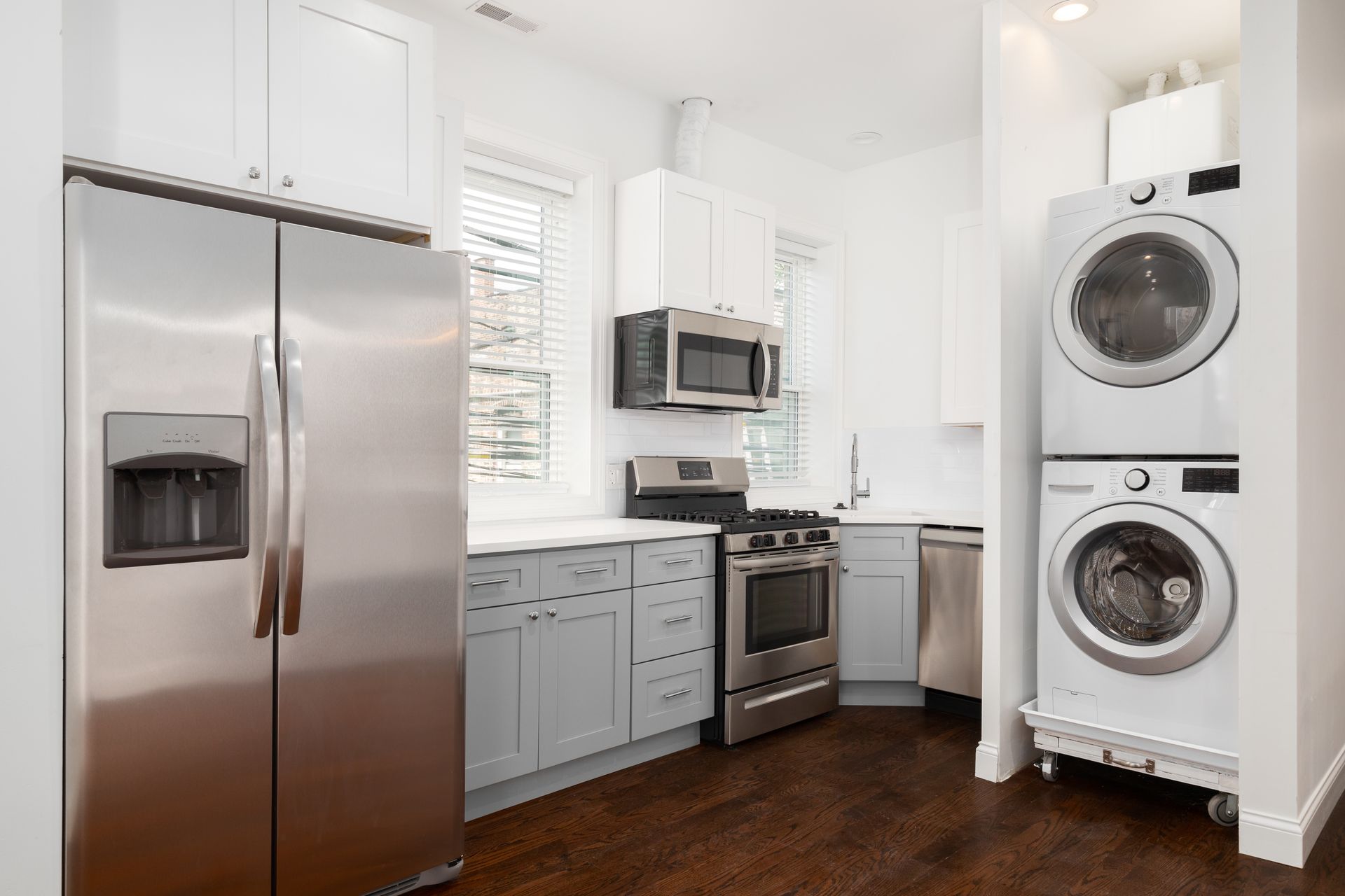 A kitchen with a refrigerator , washer and dryer stacked on top of each other.
