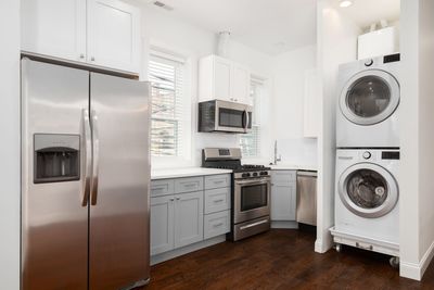 A kitchen with a refrigerator , washer and dryer stacked on top of each other.