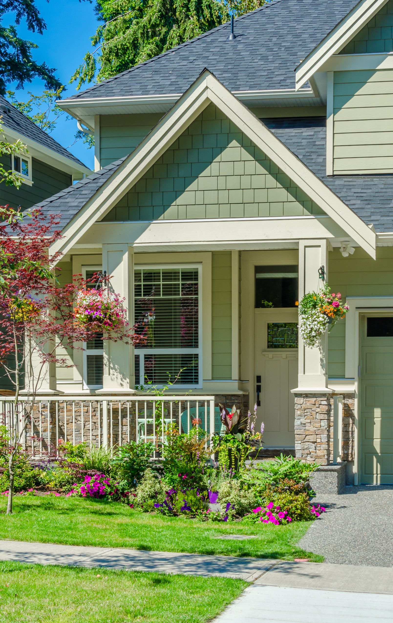 A house with a lush green lawn and flowers in front of it.