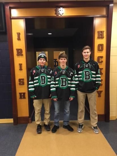 Three people in matching green sports jerseys standing in a doorway labeled “Irish.”