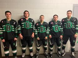 Five hockey players in black and green uniforms posing against a wall, holding their skates.