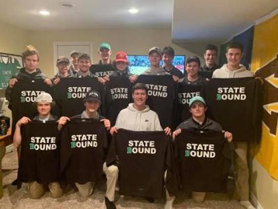 Group of people indoors holding “STATE BOUND” signs, posing together for a team photo.