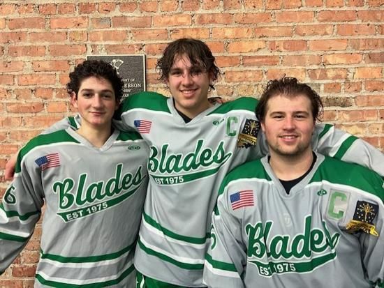 Three hockey players in gray and green Blades jerseys posing against a brick wall.