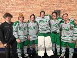 Five hockey players in green-and-white Blades uniforms posing against a brick wall