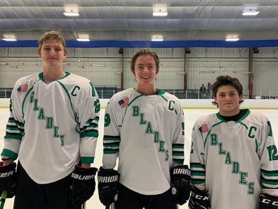 Three hockey players in white Blades jerseys standing on an indoor rink