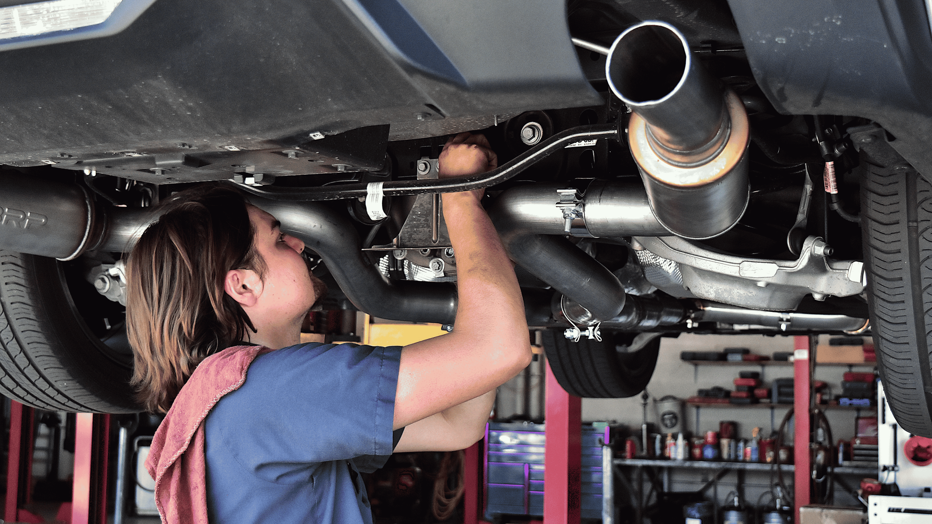 Technician installing an aftermarket exhaust system with proper fitment and alignment on a vehicle