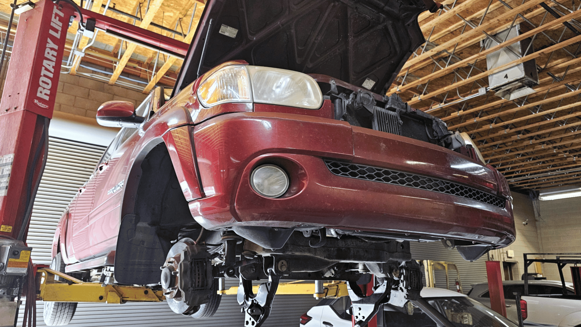 Vehicle undercarriage showing control arms, bushings, and suspension components during repair