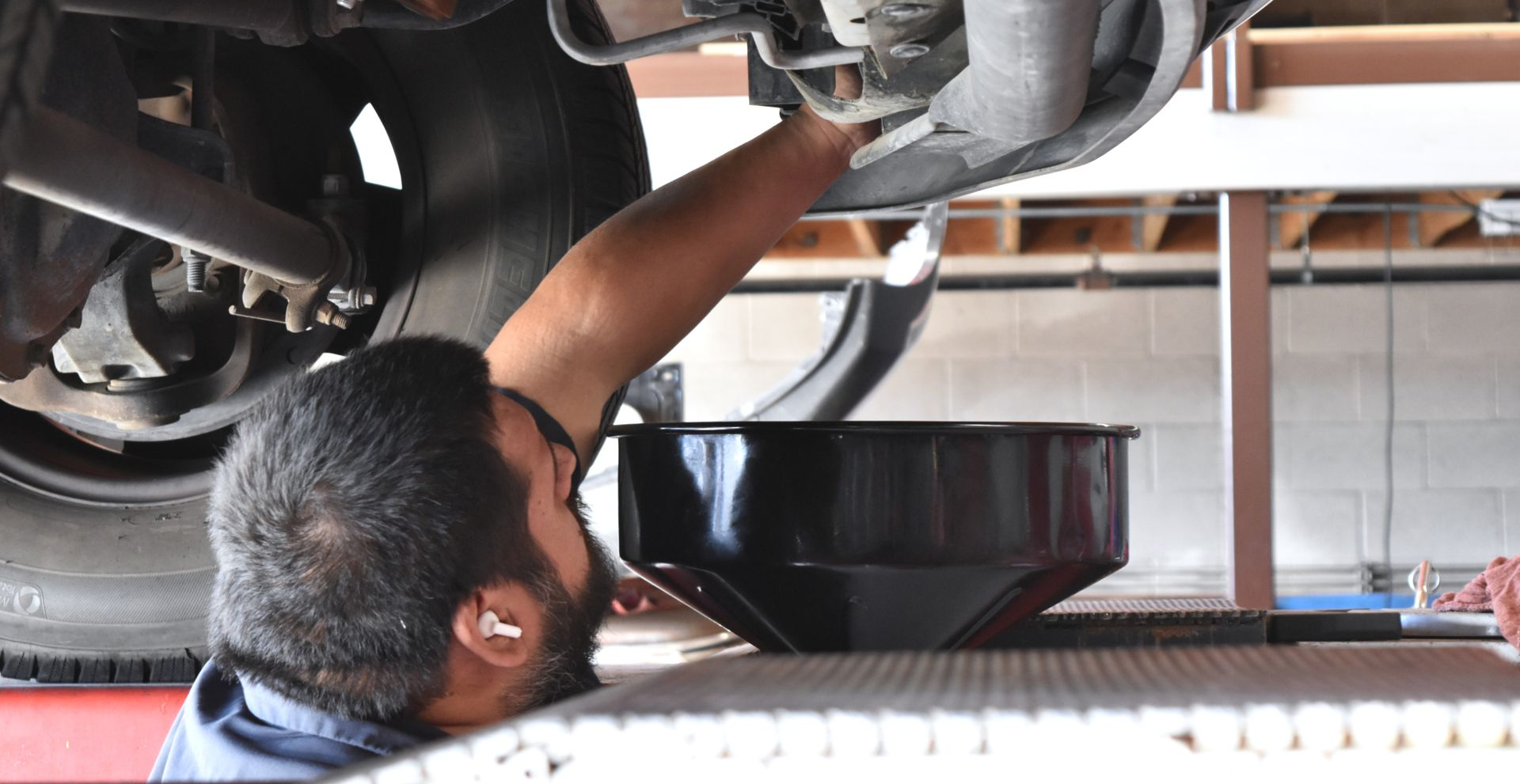 Auto repair technician performing a routine oil change on a vehicle in a service bay