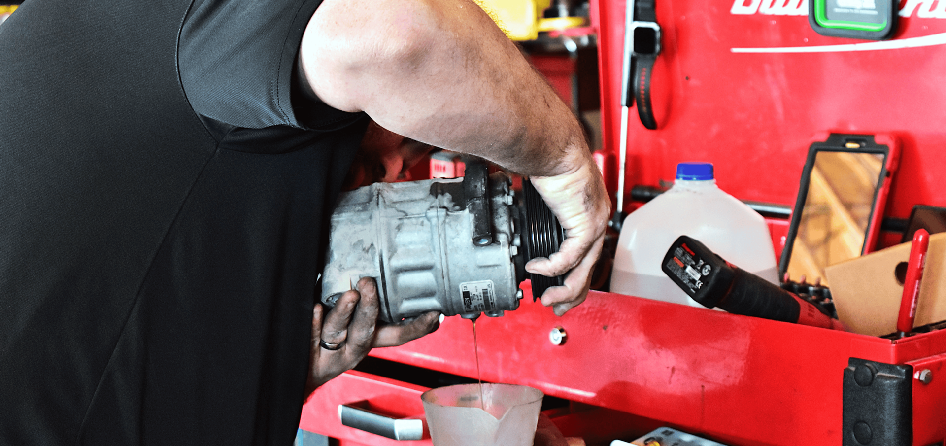 Technician draining A/C compressor oil during automotive A/C repair service in North Phoenix. | Precision Tire and Auto Center