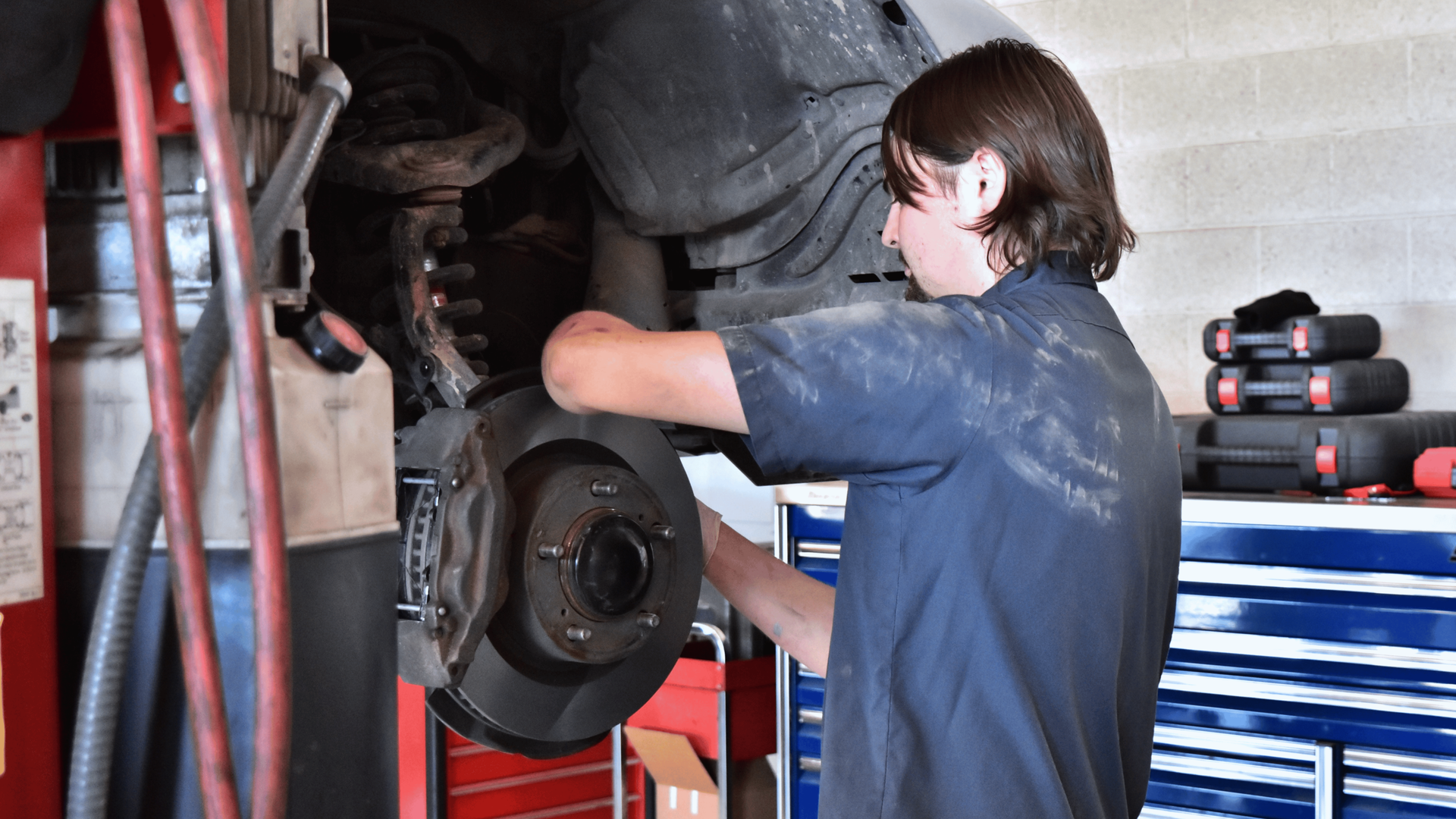 Auto technician working on a vehicle brake job supporting October Brakes for Breasts brake service