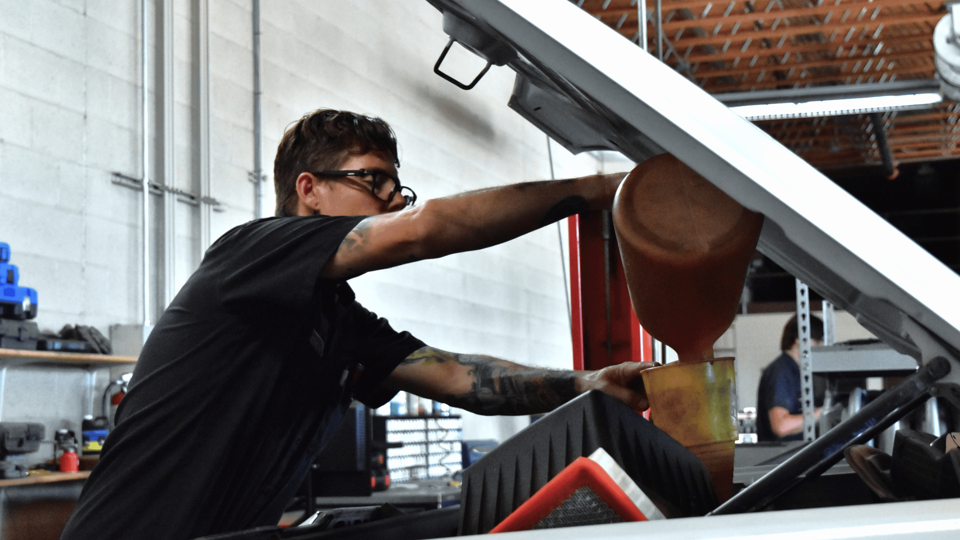 Tech performing a vehicle fluid exchange as part of routine maintenance and fluid system service