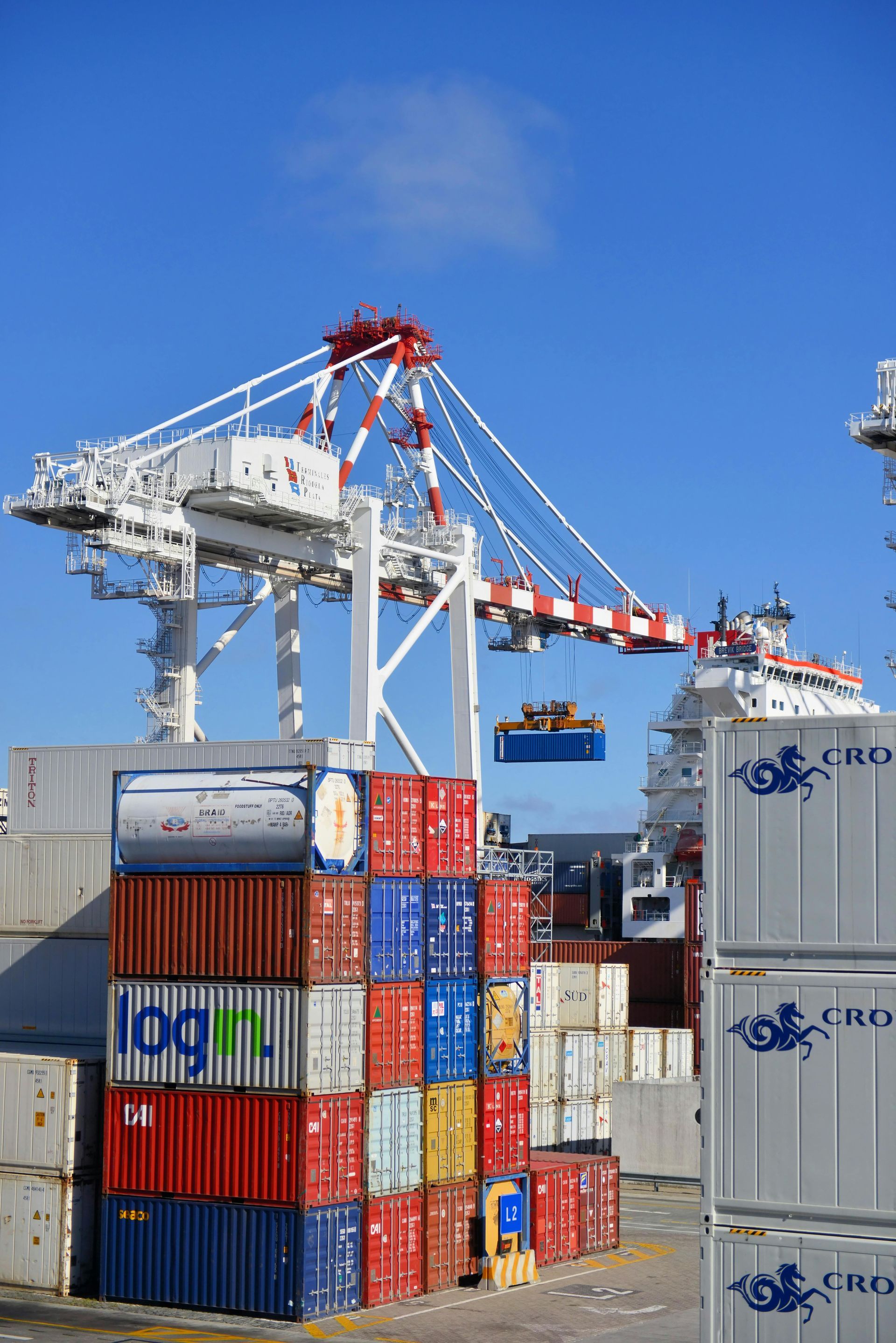 A large shipping crane moves a cargo container above shipping containers - Quality Storage Container