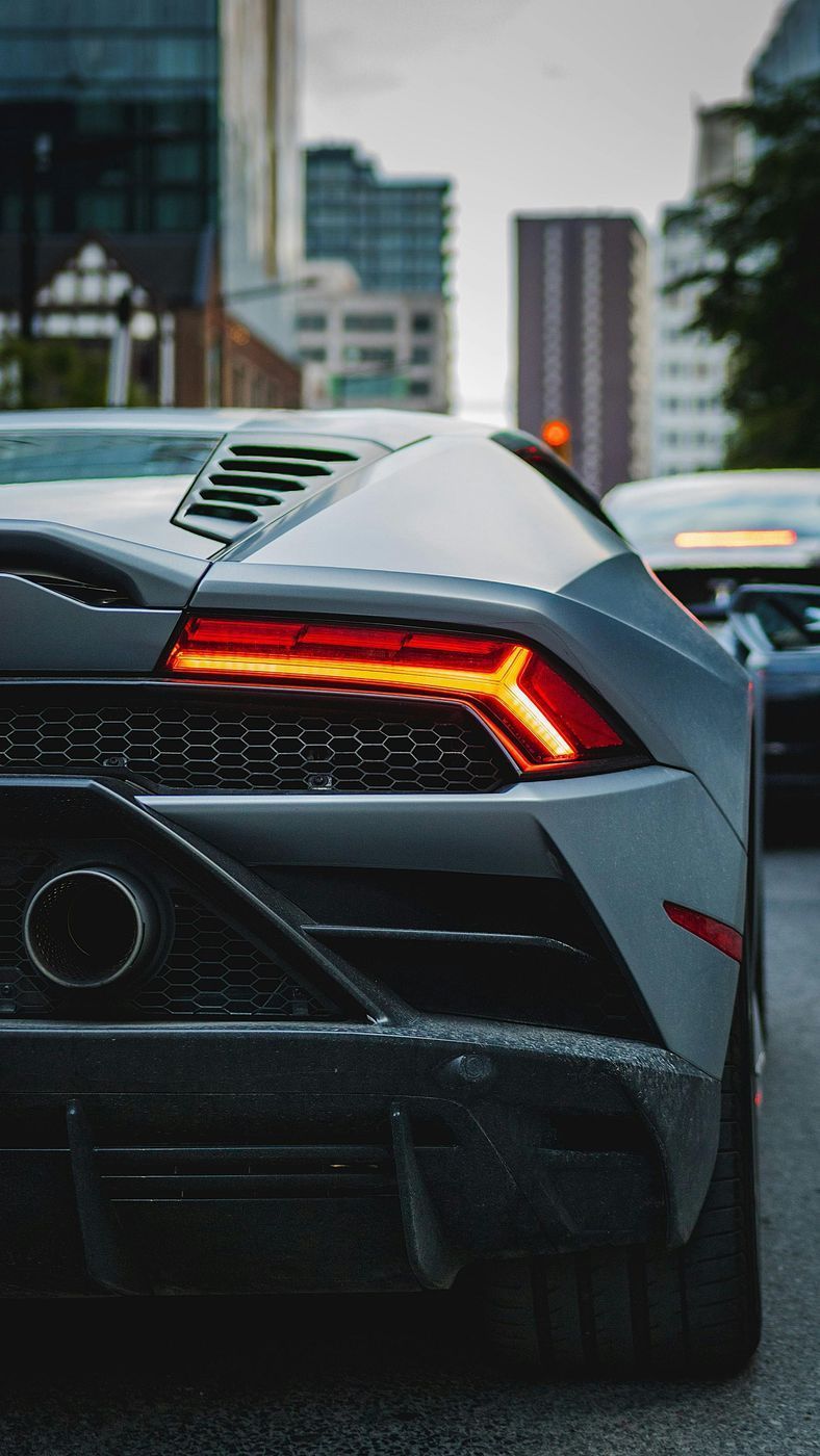 Grey Lamborghini seen from the rear in city traffic, the kind of supercar we ship from London