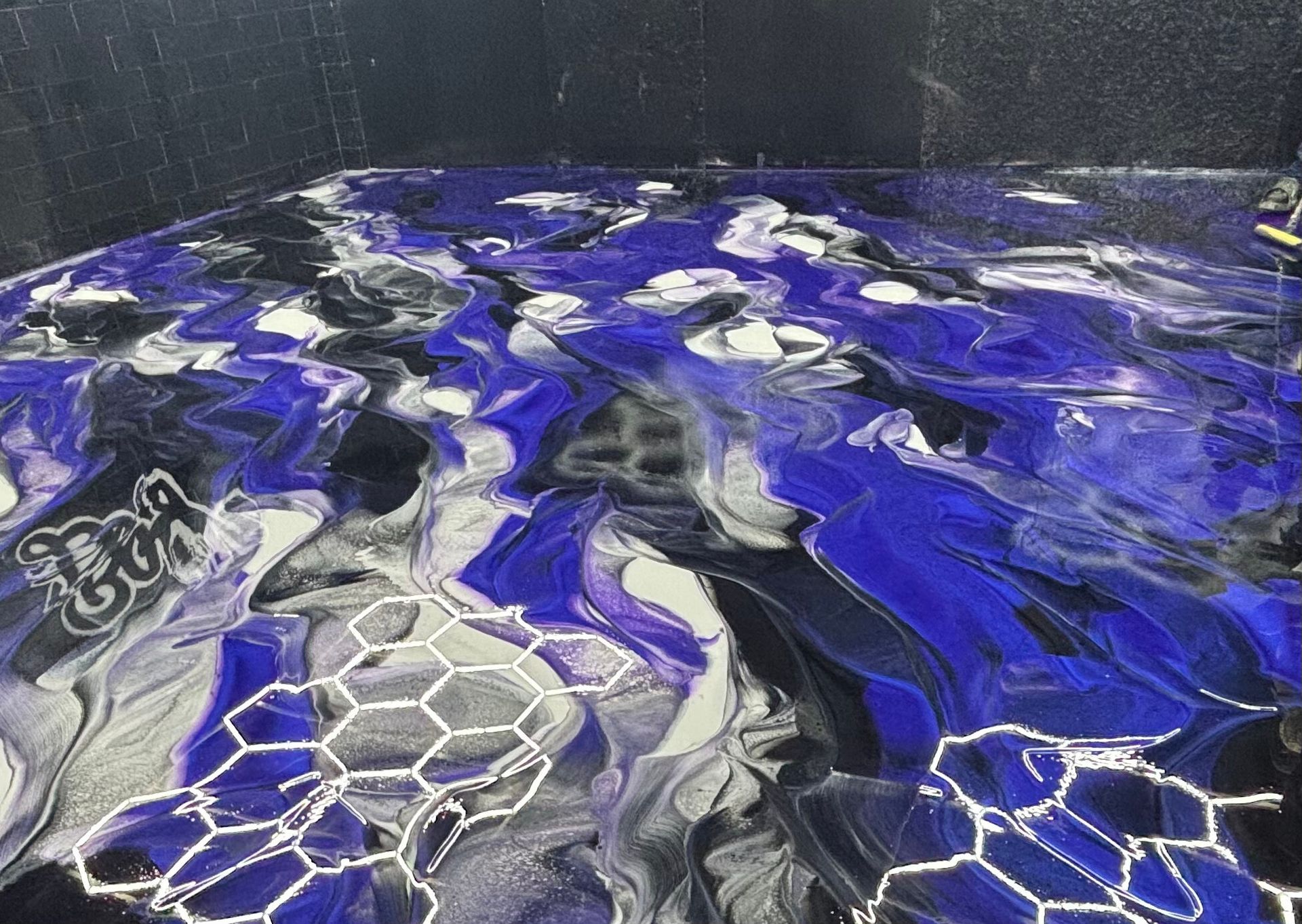 Abstract blue, white, and black marbled pattern on a glossy surface with hexagonal accents