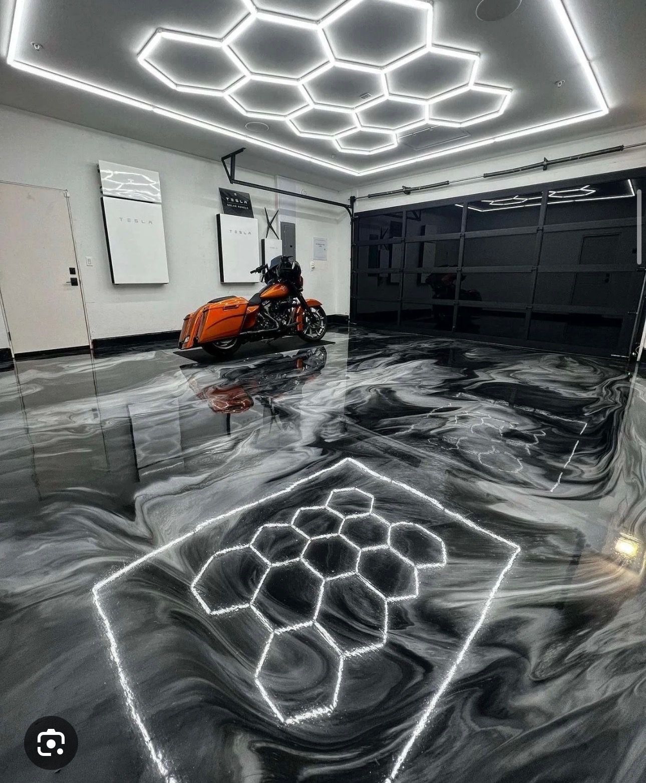 Luxury garage with glossy black floor, honeycomb LED ceiling, and an orange sports car.