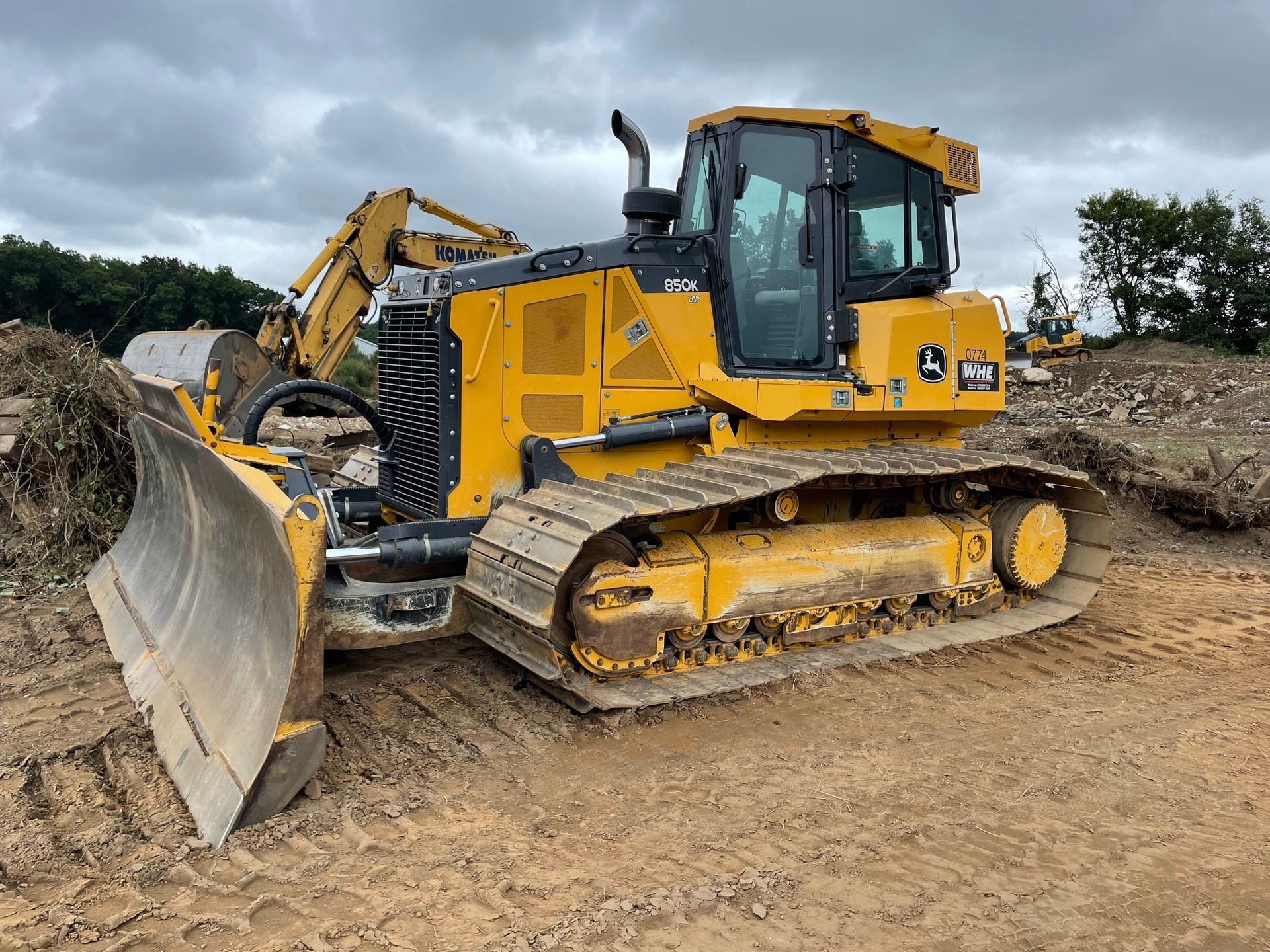 Yellow bulldozer on a construction site, with tracks and a large blade. Overcast sky.