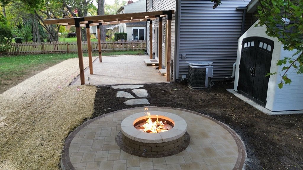 Stone patio with steps, fire pit, covered porch, and pergola with outdoor furniture.