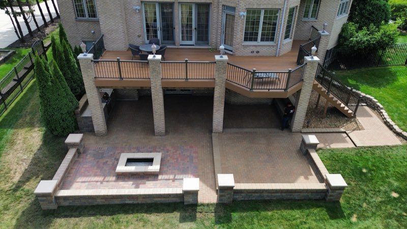 Patio with wicker furniture, a gazebo, and flower pots against a white house.