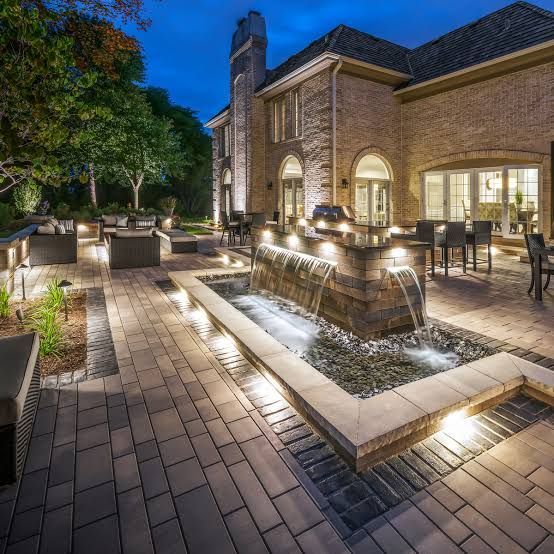 Stone steps lit with lights lead up to a wooden house at dusk.
