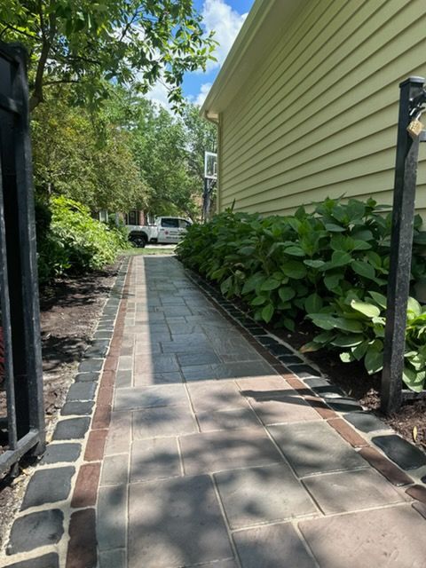 Brick pathway in a herringbone pattern leads to a circular plaza with seating and green lawn.