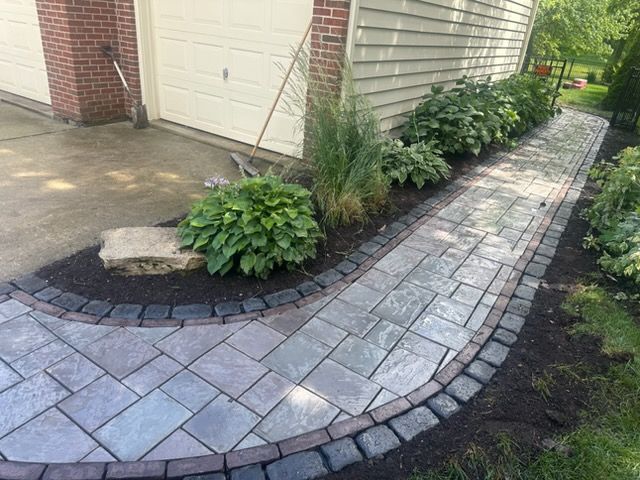 Person placing paving stones on gravel surface.