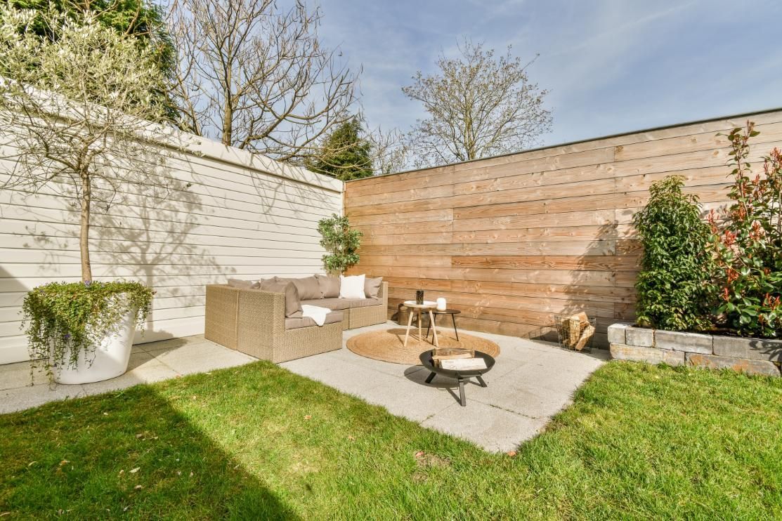 Outdoor patio with a seating area, fire pit, and wooden fence.