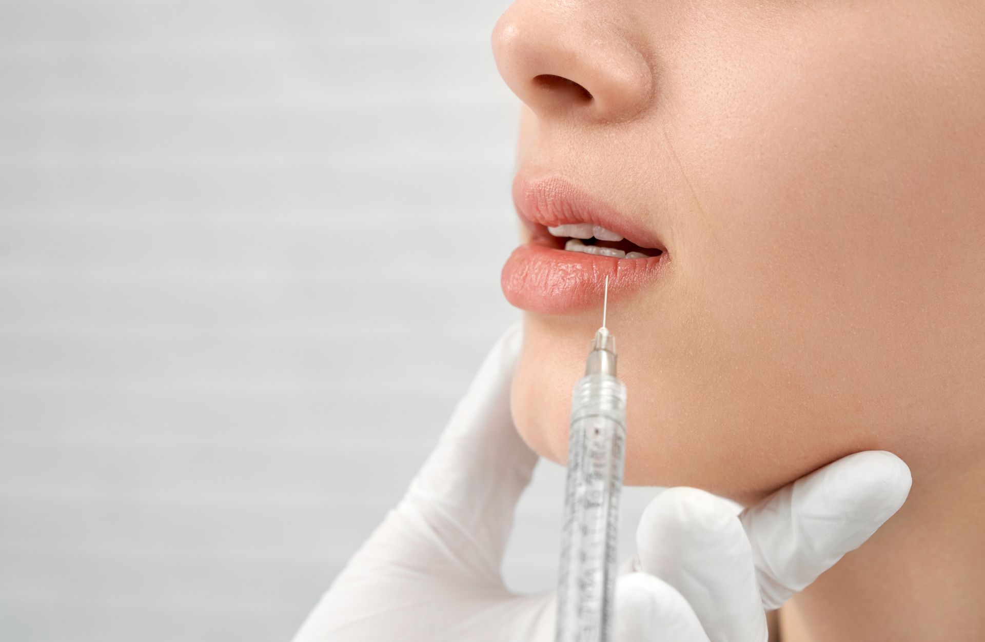 A woman is getting a botox injection in her lips.