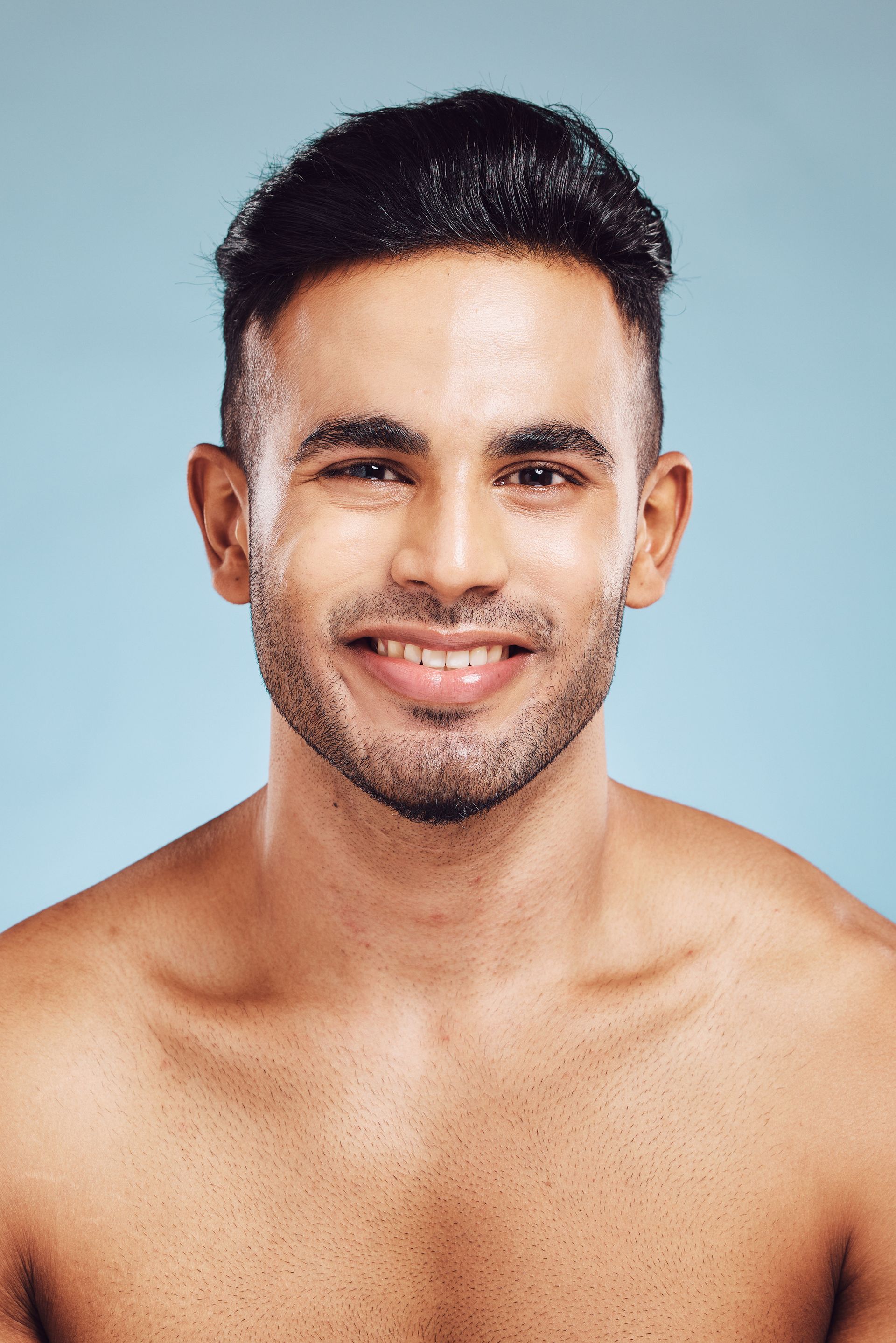 A shirtless man with a beard is smiling for the camera.