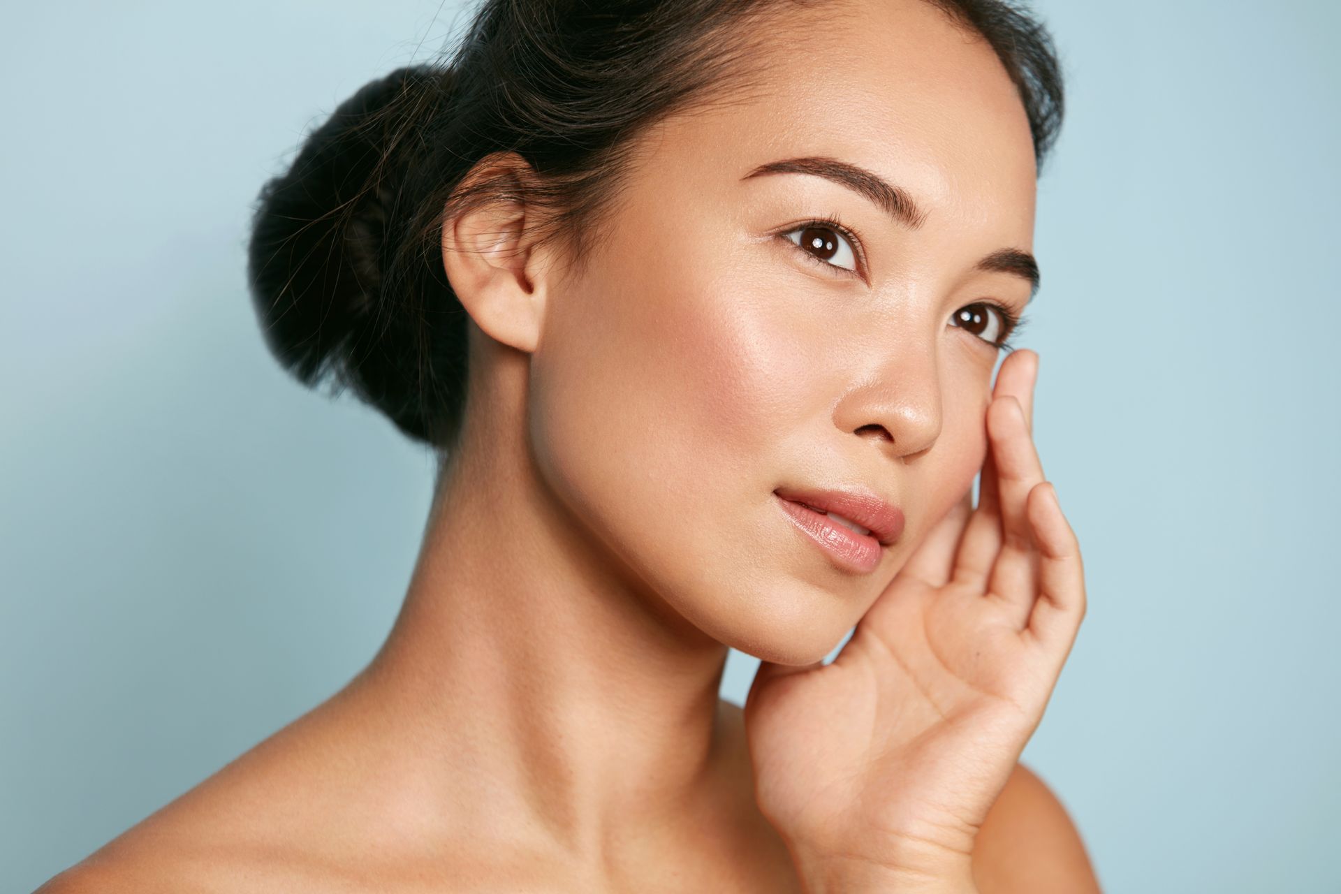 A woman is touching her face with her hand and looking at the camera.