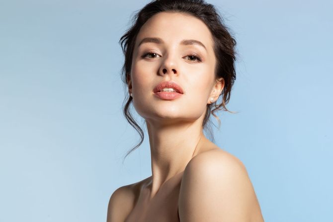 A close up of a woman 's face on a blue background.