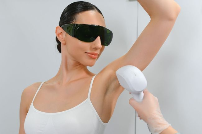 A woman is getting a laser hair removal treatment on her underarm.