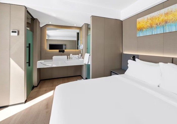 Modern hotel room with a bed and a bathroom area.