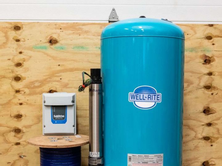 Blue Well-Rite tank beside a small white control box in a utility room against plywood walls