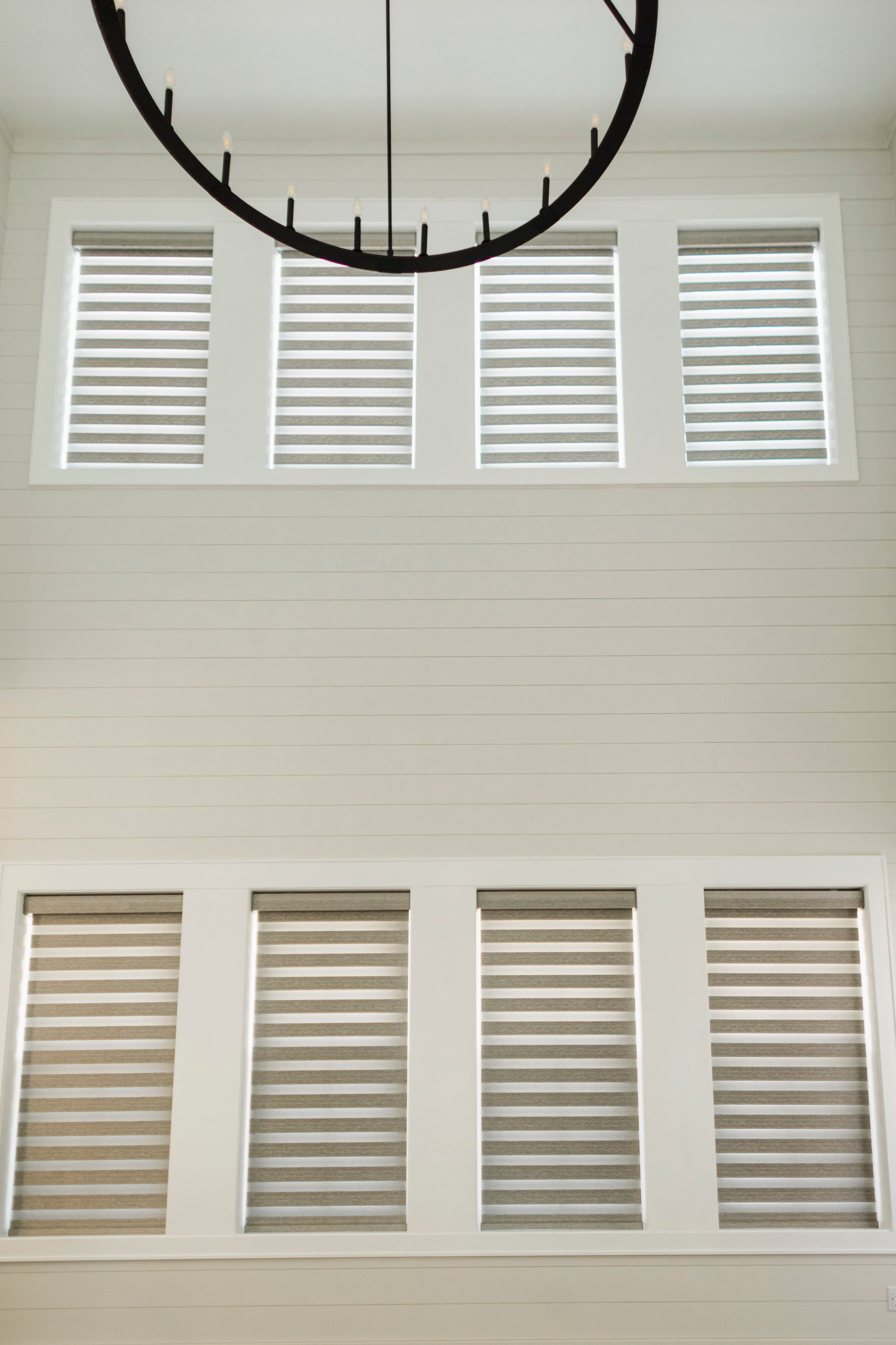 Wall with two rows of white plantation shutters beneath a black circular light fixture