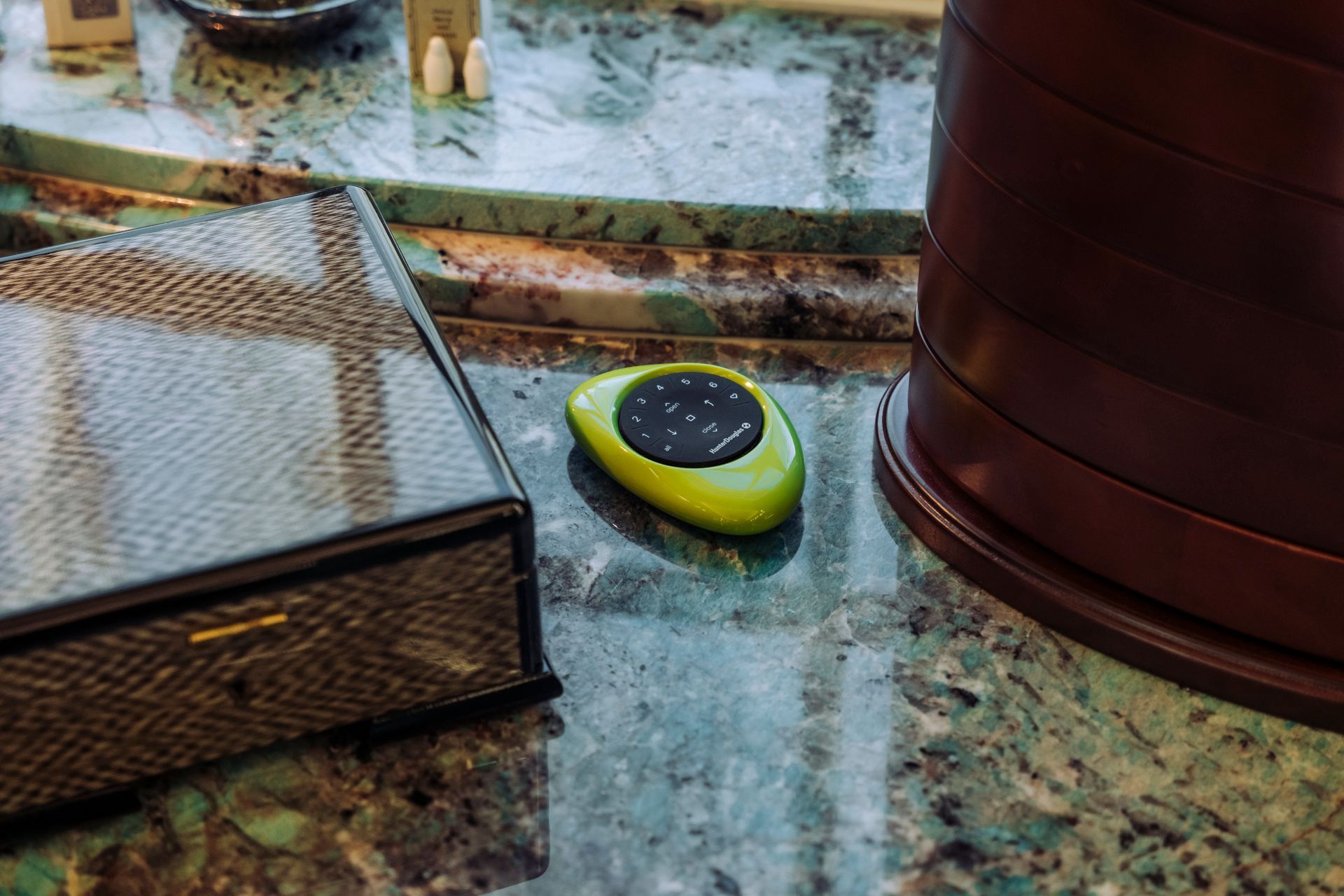 Green handheld device on a speckled countertop beside a woven basket and brown container
