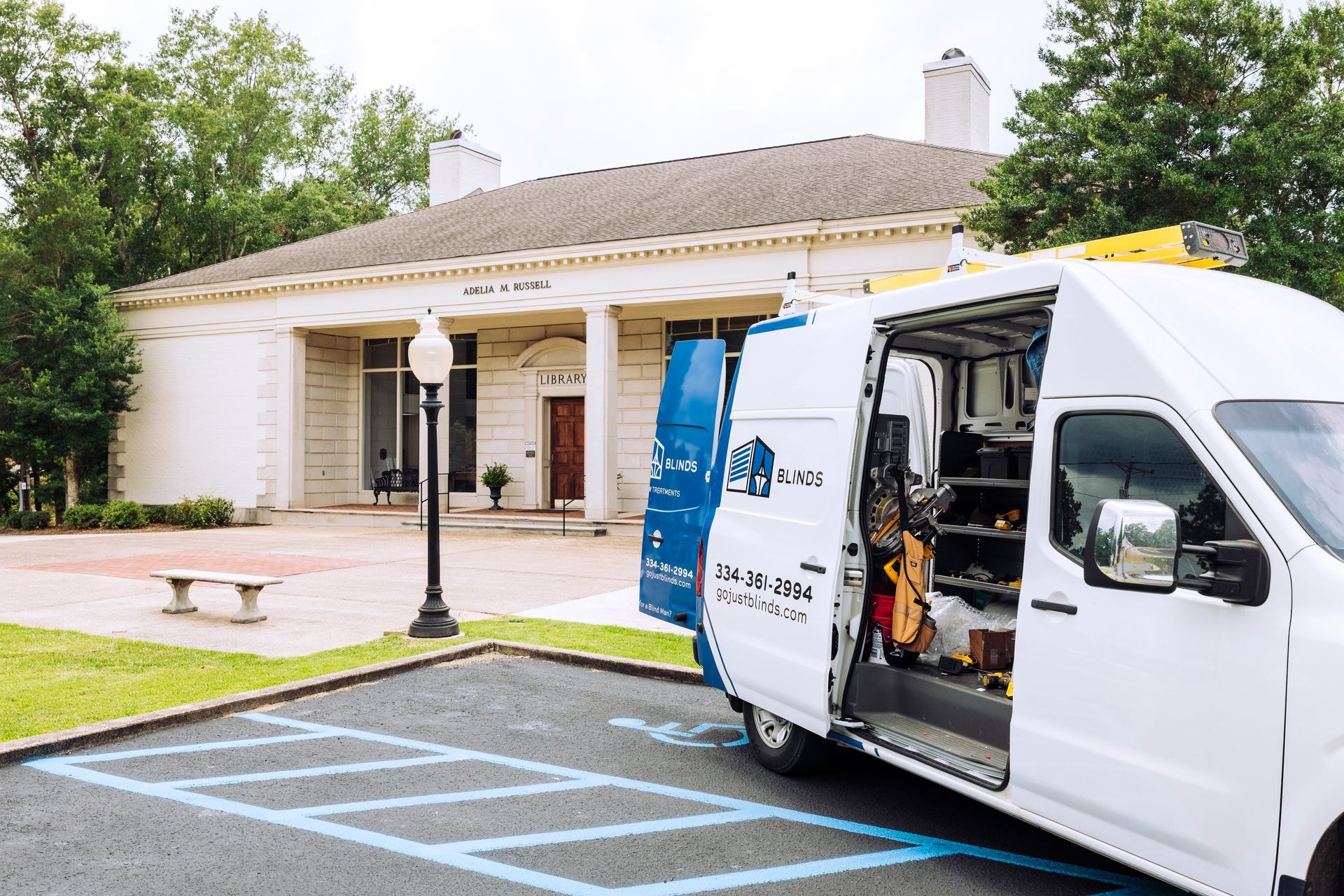 White service van with wheelchair lift parked by a building’s accessible parking spaces
