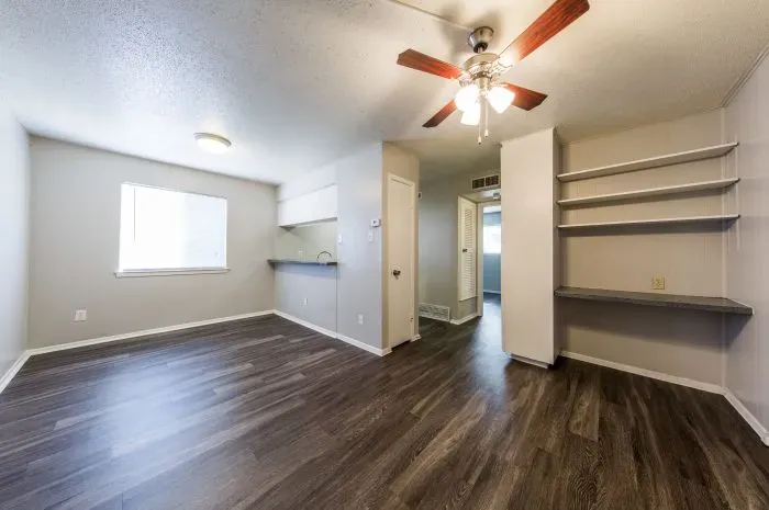 Los Arcos - living room with grey laminate wood flooring looking into kitchen.