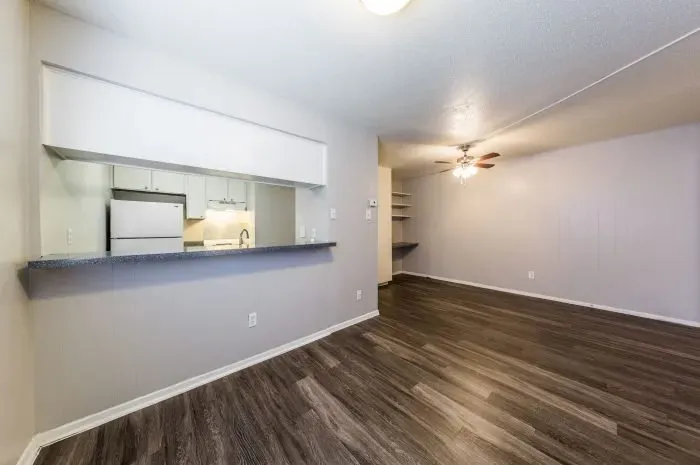 Los Arcos - living room with grey laminate wood flooring looking into kitchen.