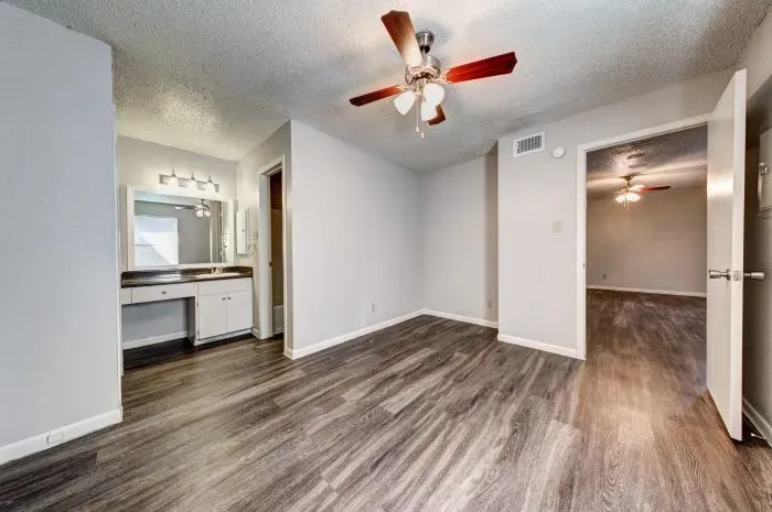 Living room with grey floors and ceiling fan and kitchen