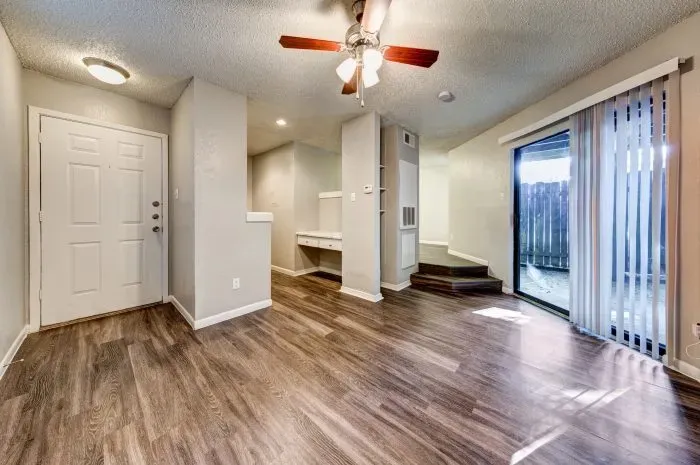 Living room with grey floors and ceiling fan and kitchen