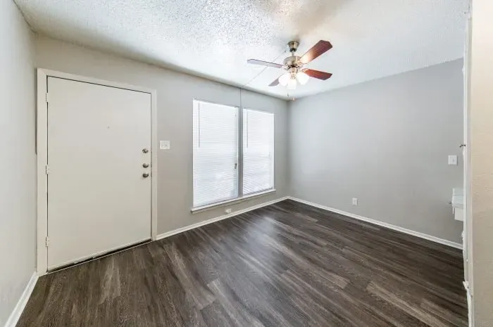 Pecan Square - living room with grey laminate flooring and ceiling fan.
