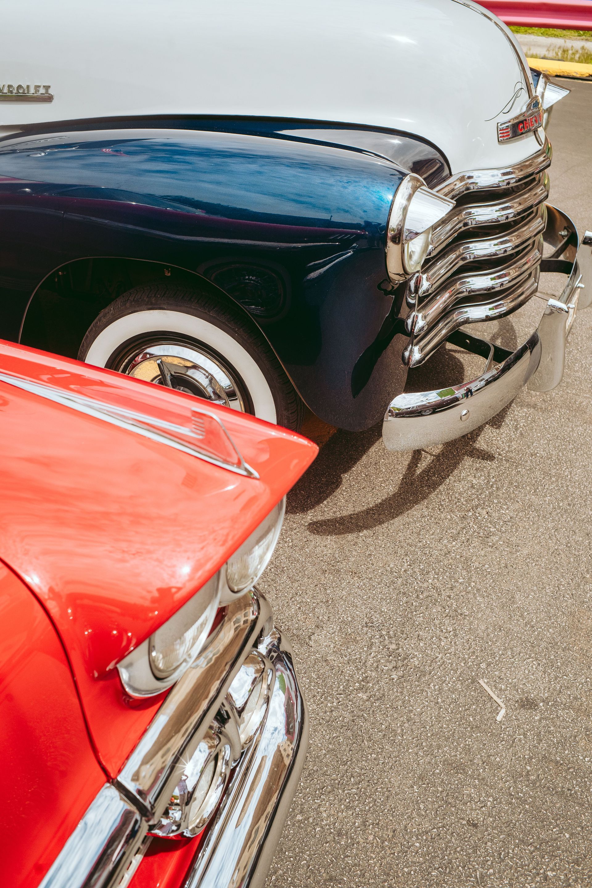 Close-up of two classic cars, one red and one dark blue, parked side by side.