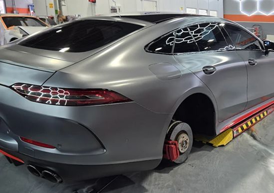 Silver sports coupe on a car lift with wheel clamps in a garage/workshop