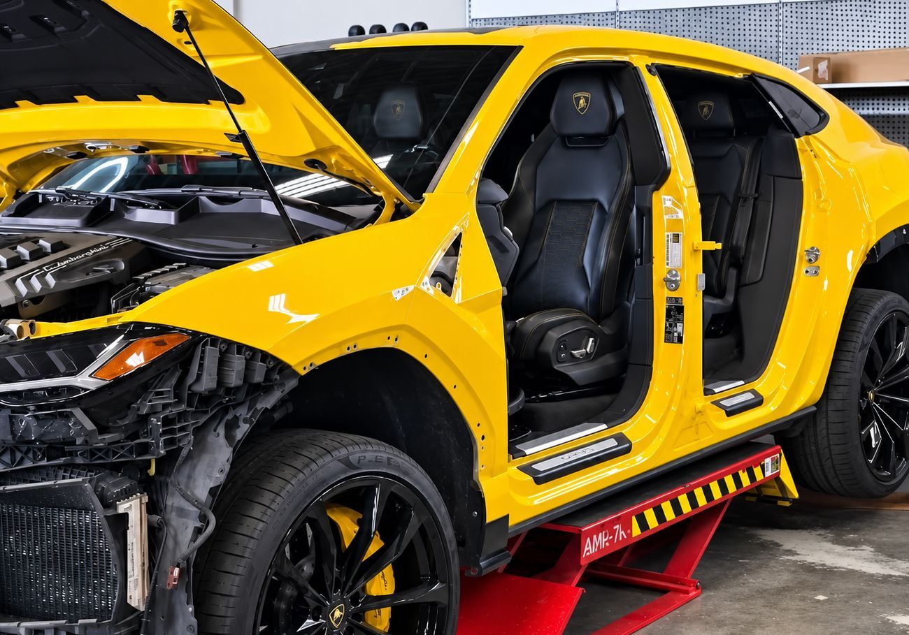 Yellow car with open hood and missing doors on a red lift in a garage